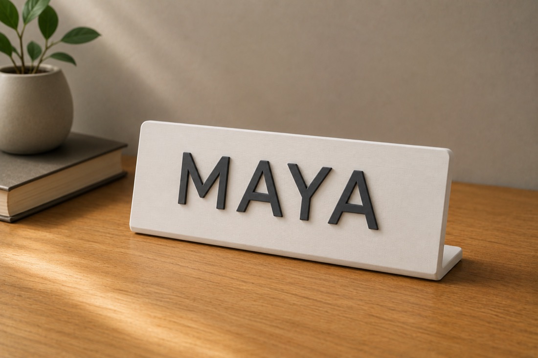 A white 3D-printed desk name plate with raised dark lettering on an angled stand